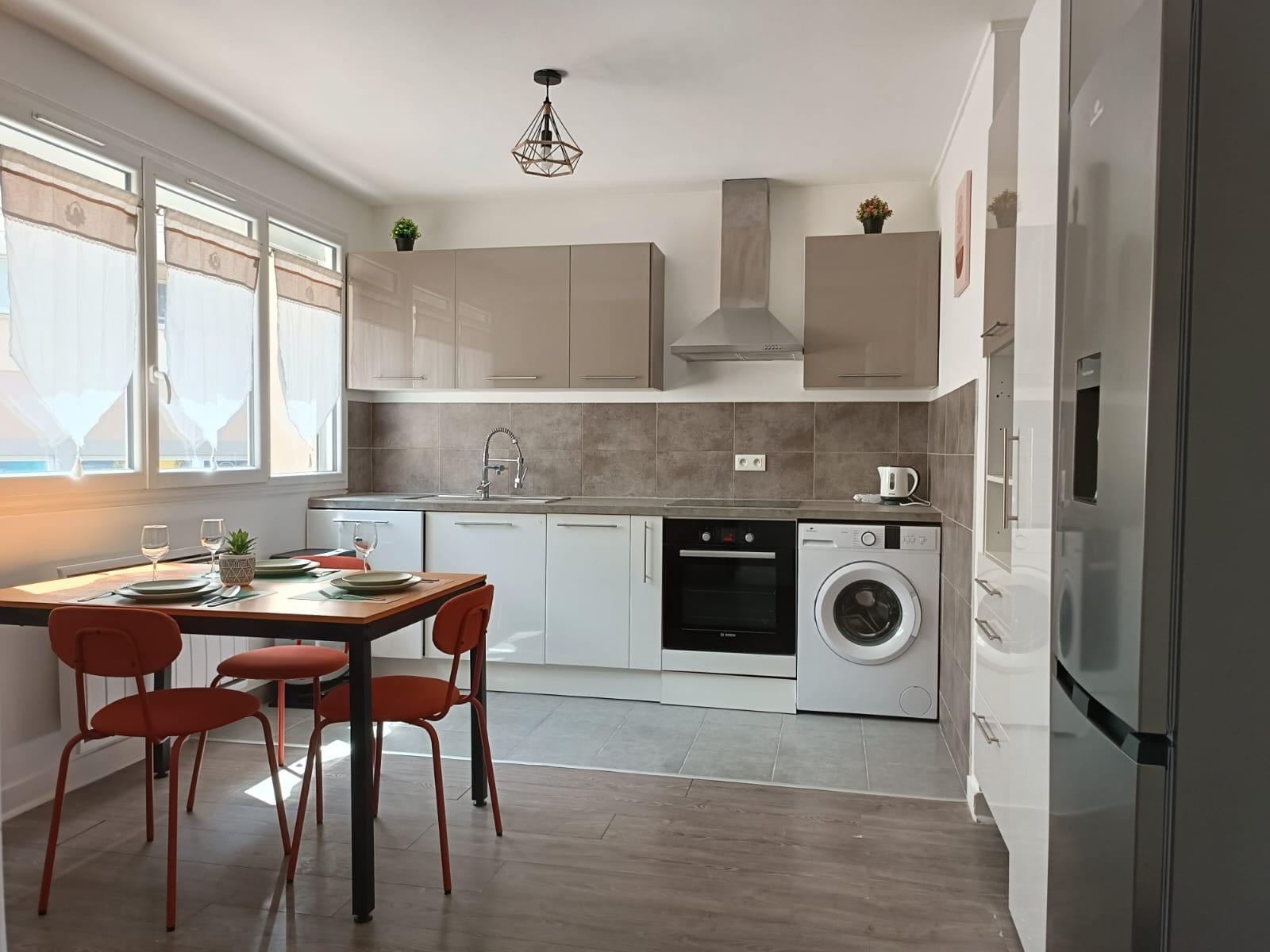 Cuisine ouverte avec plan de travail, carrelage gris et table à manger